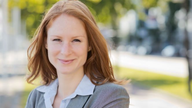 Red-headed woman in business clothes smiling